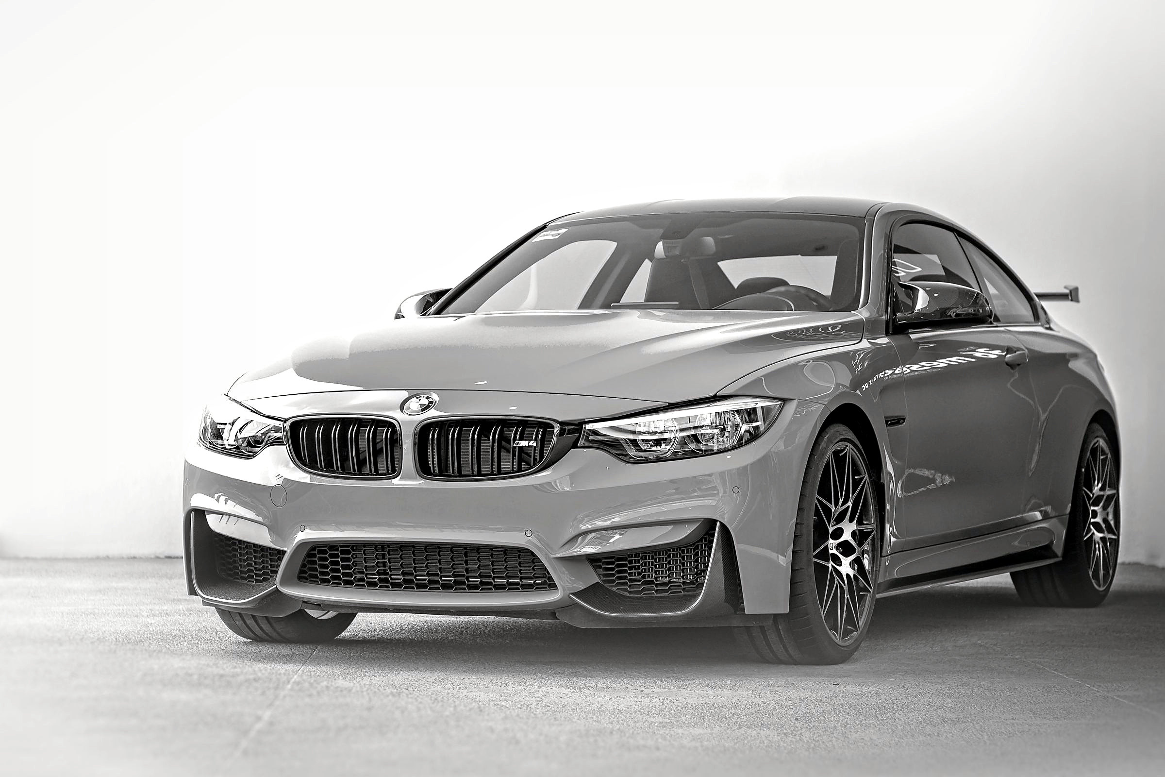 Graues BMW-Coupé von schräg vorne vor heller Wand